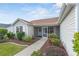 Tan house with landscaped yard, screened porch, and attached garage at 17848 Se 87Th Bourne Ave, The Villages, FL 32162