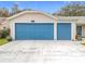 Two-car garage with blue doors and a concrete driveway at 4817 Summerbridge Cir, Leesburg, FL 34748