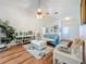 Living room features hardwood floors, a comfy teal sofa, and a large window at 4817 Summerbridge Cir, Leesburg, FL 34748