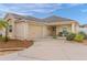Tan house with palm tree, landscaped yard, and two-car garage at 9224 Se 167Th Ford St, The Villages, FL 32162
