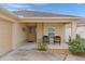Tan house with covered entryway, two chairs, and landscaping at 9224 Se 167Th Ford St, The Villages, FL 32162