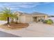 Tan house with palm tree, landscaped yard, and two-car garage at 9224 Se 167Th Ford St, The Villages, FL 32162
