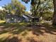 Gray house with red door, and a large yard with mature trees at 13705 Se 25Th Ave, Summerfield, FL 34491