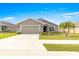 Single-story home with gray siding, two-car garage, and landscaped yard at 16178 Se 104Th Ter, Summerfield, FL 34491