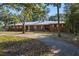 Brick ranch home with metal roof and long driveway, surrounded by trees at 22740 County Road 44A, Eustis, FL 32736
