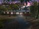 Brick home with metal roof, long driveway, and mature landscaping at dusk at 22740 County Road 44A, Eustis, FL 32736