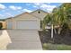 House exterior featuring a two-car garage and palm trees at 3810 Cosmos Way, The Villages, FL 32163