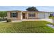 Tan house with brown shutters, attached garage, and well-manicured lawn at 2001 Castano Pl, The Villages, FL 32159