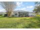 Large backyard with grassy lawn, trees, and screened enclosure at 27437 Desert Rose Ct, Leesburg, FL 34748