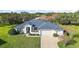 One-story home with a blue roof, two-car garage, and landscaped yard at 27437 Desert Rose Ct, Leesburg, FL 34748