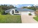 Single-story house with blue roof, two-car garage, and well-manicured lawn at 27437 Desert Rose Ct, Leesburg, FL 34748