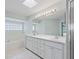 Bathroom with double vanity, large mirror, and skylight at 5126 County Road 125, Wildwood, FL 34785