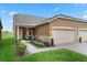 Two-story house with tan exterior, two-car garage, and landscaped front yard at 2676 Spider Lily Ct, Clermont, FL 34711