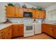 L-shaped kitchen with wood cabinets and white appliances at 8203 Village Dr # 8203, Lake Wales, FL 33898