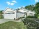 Charming one-story house with a white exterior, green landscaping, and two-car garage at 341 Lake Suzanne Dr, Lake Wales, FL 33859