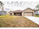 Newly constructed one-story home with a light brown exterior, two-car garage, and a spacious lawn at 3671 E Gaskins Rd, Bartow, FL 33830