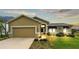 Tan house with a two-car garage, lush lawn, and landscaping at 5879 Swallow Dr, Lakeland, FL 33809