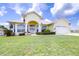 Beautiful yellow house with a large front yard, two-car garage, and lush landscaping at 6764 Bendelow Dr, Lakeland, FL 33810