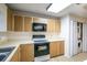 Kitchen with wood cabinets, stove, microwave, and laundry closet at 832 S Hill Ave # 10, Deland, FL 32724
