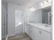 Main bathroom with double sinks, gray tile shower, and a large mirror at 2856 San Marco Way, Winter Haven, FL 33884