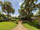 Landscaped backyard with stone path, lush greenery, and large oak trees at 1323 Hammock Shade Dr, Lakeland, FL 33809