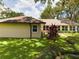 Tan house exterior with brown roof, landscaping, and large trees at 1323 Hammock Shade Dr, Lakeland, FL 33809