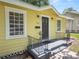 Charming yellow house with a black door, gray walkway, and well-manicured lawn at 714 Winfree Ave, Lakeland, FL 33801