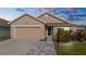 Tan house with a two-car garage, landscaping, and brick paver driveway at 6094 Eagle Pointe Dr, Lakeland, FL 33812