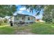 Mobile home with covered patio, grassy yard, and partial fence at 1610 Reynolds Rd # 50, Lakeland, FL 33801