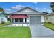 Single-story home with a gray garage door, red awning, and landscaped yard at 6205 Raven Run, Lakeland, FL 33809