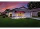 Single-story home with a gray garage door, red awning, and landscaped yard at dusk at 6205 Raven Run, Lakeland, FL 33809