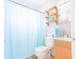 Clean bathroom with light blue shower curtain, wooden vanity, and floating shelves at 121 Coleman Rd, Winter Haven, FL 33880