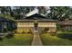 Tan Bungalow style home with a walkway, landscaping, and a well-maintained lawn at 1127 N Stella Ave, Lakeland, FL 33805
