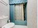 Bathroom with shower/tub combo, teal colored fixtures and blue curtains at 92 Wood Hall Dr, Mulberry, FL 33860