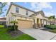 Two-story house with beige siding, a two-car garage, and landscaping at 7004 Oakwood St, Davenport, FL 33837