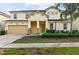 Two-story house with beige siding, a three-car garage, and landscaping at 7004 Oakwood St, Davenport, FL 33837