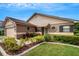 Tan one-story house with a two-car garage, mature shrubs, and a walkway at 6256 Sandpipers Dr, Lakeland, FL 33809
