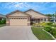 Beige house with two-car garage, landscaped lawn, and a walkway to the front door at 6256 Sandpipers Dr, Lakeland, FL 33809