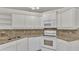White kitchen cabinets, granite countertops and a corner sink at 5873 Macaw Pl, Lakeland, FL 33809