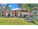 Single-story home with red accents and a lush green lawn at 1555 Archers Path, Lakeland, FL 33809