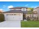 Two-story house with a two-car garage, landscaping, and a light beige exterior at 2199 Ontario Way, Lakeland, FL 33805