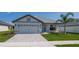 One-story home with gray siding, light gray garage door, and landscaped yard at 4437 Juliana Lake Dr, Auburndale, FL 33823