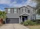 Two-story house with gray siding, dark garage door, and landscaping at 1918 Wind Meadows Dr, Bartow, FL 33830