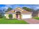 Charming single-story home with a red door, landscaped yard, and brick driveway at 3226 Oak Tree Ln, Winter Haven, FL 33884