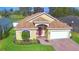 Charming single-story home with a red door, landscaped yard, and brick driveway at 3226 Oak Tree Ln, Winter Haven, FL 33884