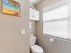 Small bathroom with toilet, storage cabinets, and window blinds at 535 Narrow Pond Rd, Polk City, FL 33868