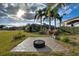 Paved patio area in a landscaped backyard with palm trees and a fire pit cover at 561 Meandering Way, Polk City, FL 33868