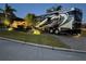 Modern RV parked on a paved area next to a landscaped lawn at 561 Meandering Way, Polk City, FL 33868