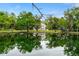 House reflecting in a pond, surrounded by lush greenery and large trees at 1795 Hideaway Ln, Edgewater, FL 32141