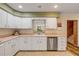 Clean, white kitchen featuring stainless steel dishwasher and view of staircase at 299 W Hickory Ave, Oak Hill, FL 32759